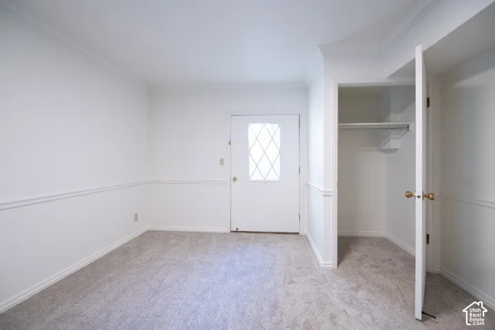 Room interior featuring wall-to-wall carpeting, crown molding, chair rail trim, and a built-in closet with integrated shelving