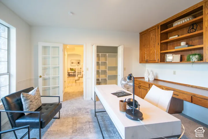 Custom wood cabinetry with integrated shelving, built-in desk surface, French doors with glass panes, and bi-fold closet doors with interior organization shelving
