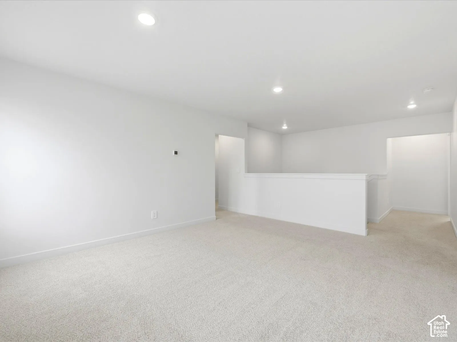 Neutral-toned wall-to-wall carpeting, crisp white walls, recessed ceiling lighting, and a partial height partition wall
