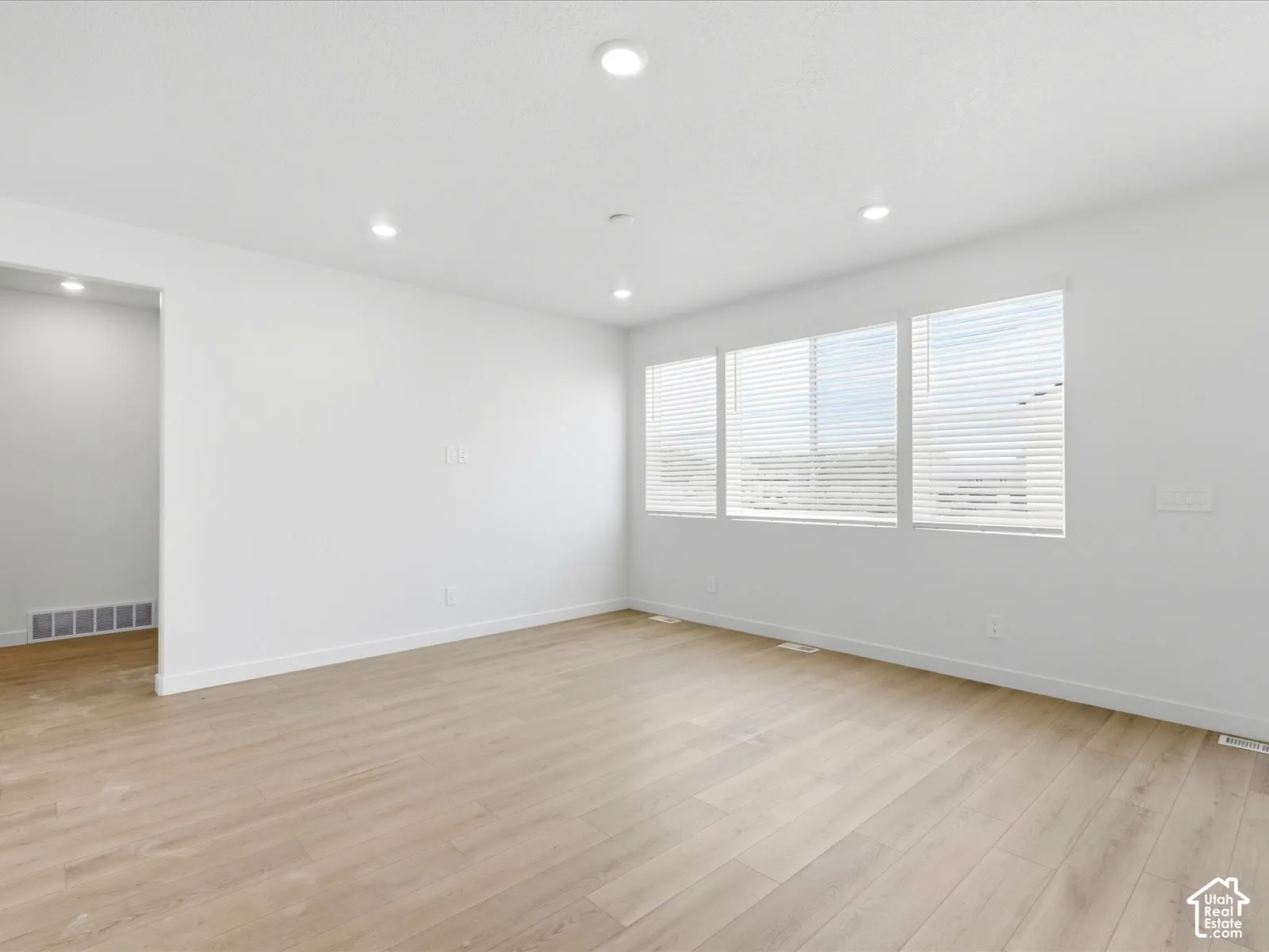 **DISCLAIMER**  Interior package may vary. Interior room featuring wood-finish flooring, recessed lighting, and expansive windows with horizontal blinds
