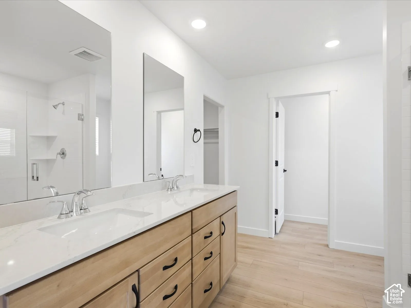 **DISCLAIMER**  Interior package may vary. Dual-sink vanity with light wood-finish cabinetry, quartz countertops, frameless vanity mirrors, and recessed lighting