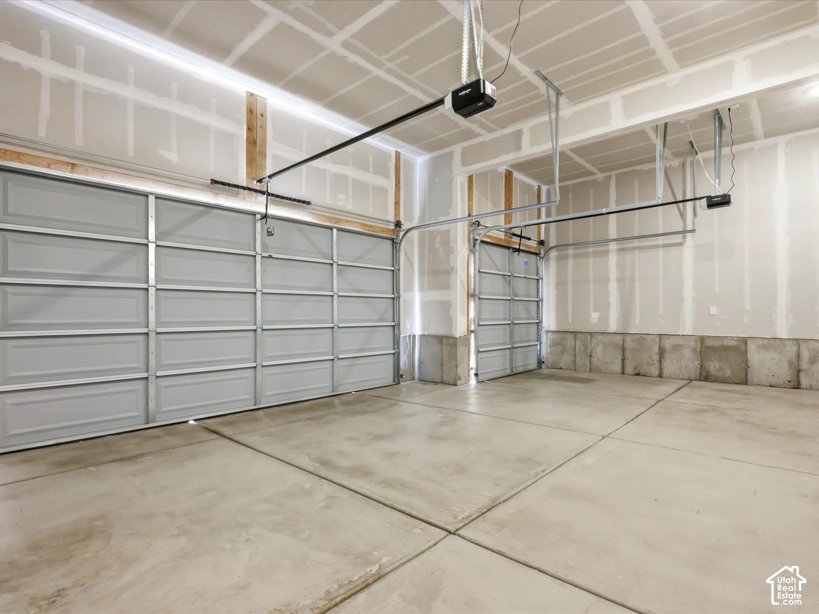 Three-car garage featuring a concrete floor, two automatic garage door openers, and individual metal panel doors