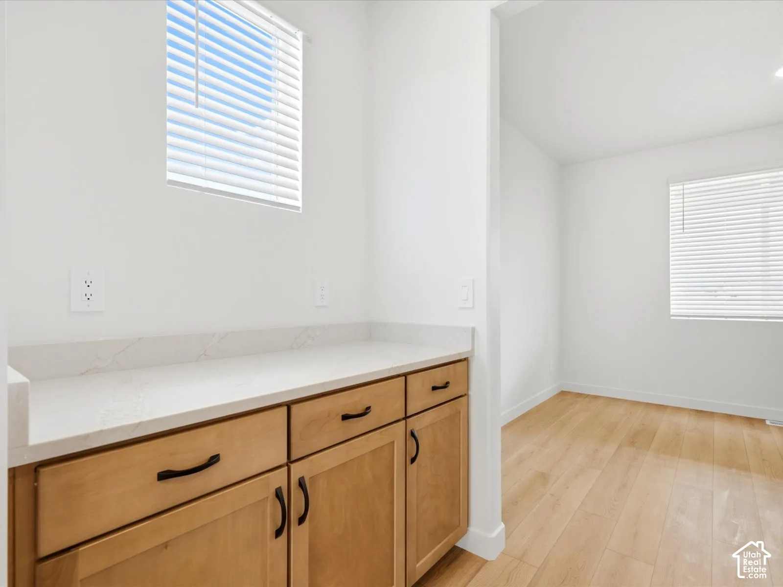 **DISCLAIMER**  Interior package may vary. Light-toned cabinetry featuring matte black hardware, quartz countertops, horizontal blind window treatments, and wood-finish flooring