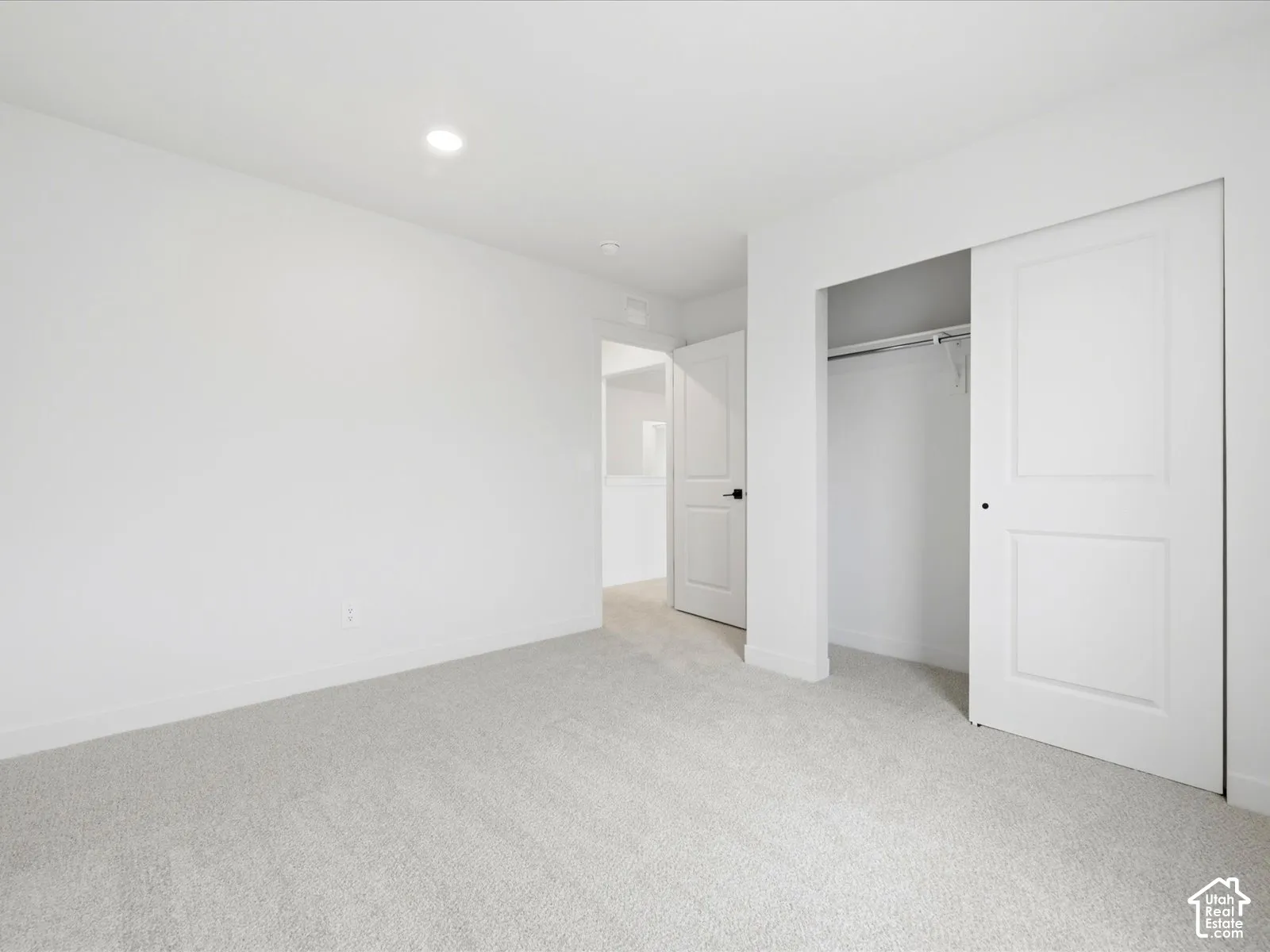 Neutral-toned carpet flooring, recessed lighting, sliding closet door, and interior doors with matte black hardware