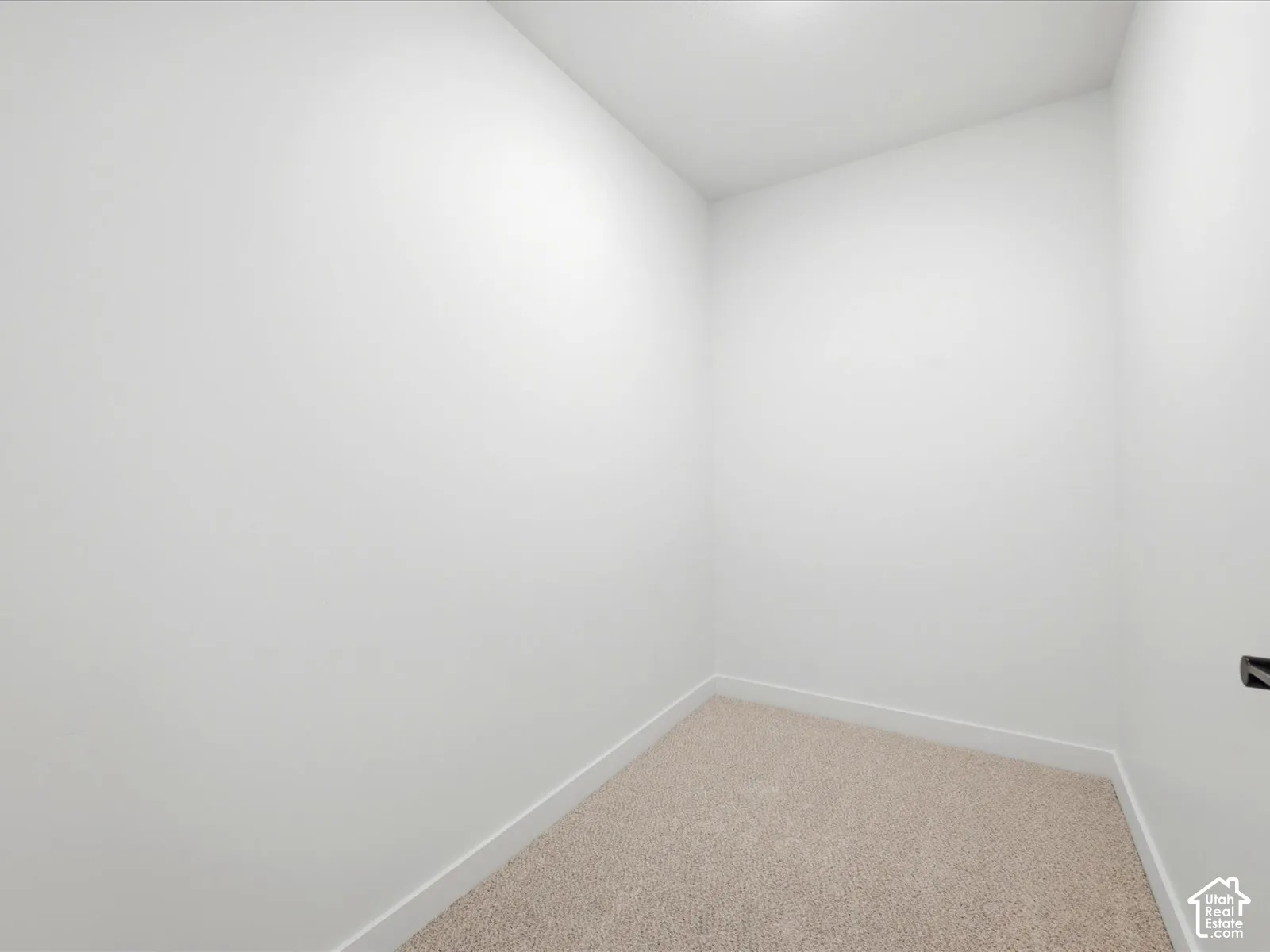 Neutral-toned interior space featuring light-colored wall-to-wall carpeting and crisp white wall finishes