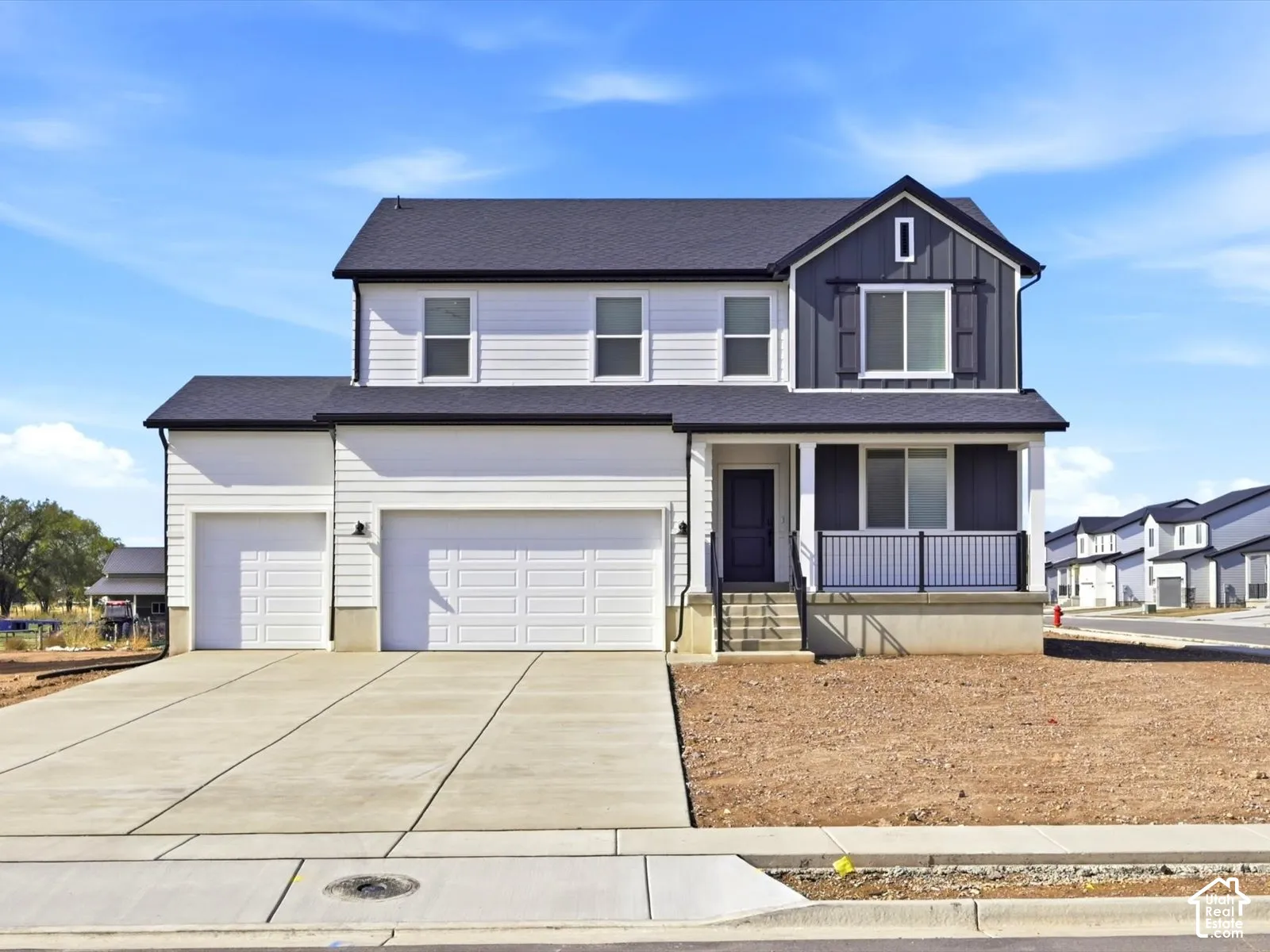Two-story exterior featuring white horizontal siding, dark vertical paneling, a three-car garage, and a covered front porch with a black metal railing