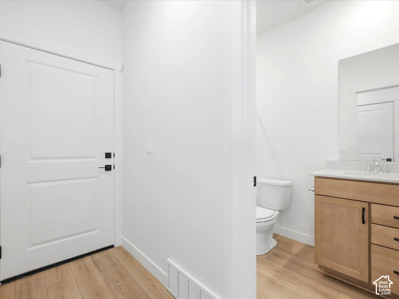 **DISCLAIMER**  Interior package may vary. Wood-finish flooring, shaker-style wooden vanity with stone countertop, rectangular undermount sink, matte black hardware, and wall-mounted vanity mirror