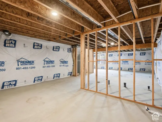 Unfinished basement area featuring exposed engineered floor joists, concrete flooring, and stud-framed interior walls