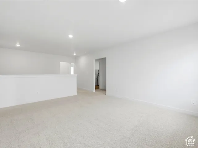 Neutral wall-to-wall carpeting, recessed ceiling lighting, and a half-wall partition