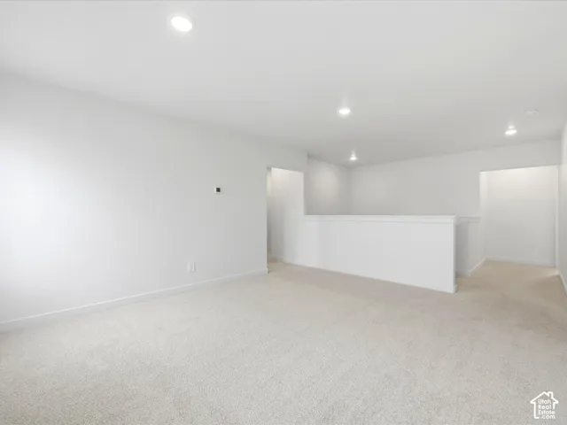 Neutral-toned wall-to-wall carpeting, crisp white walls, recessed ceiling lighting, and a partial height partition wall