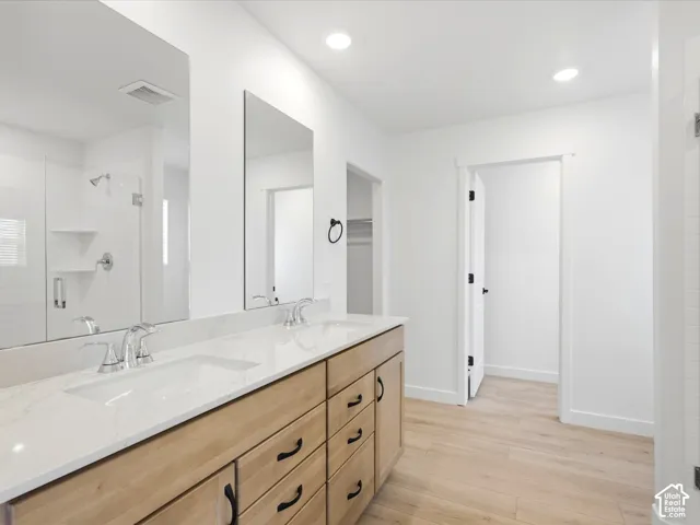 **DISCLAIMER**  Interior package may vary. Dual-sink vanity with light wood-finish cabinetry, quartz countertops, frameless vanity mirrors, and recessed lighting