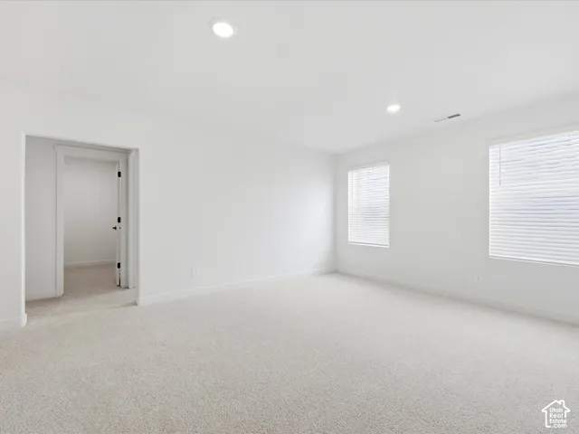 Neutral-toned wall-to-wall carpeting, recessed ceiling lighting, and windows featuring horizontal blinds