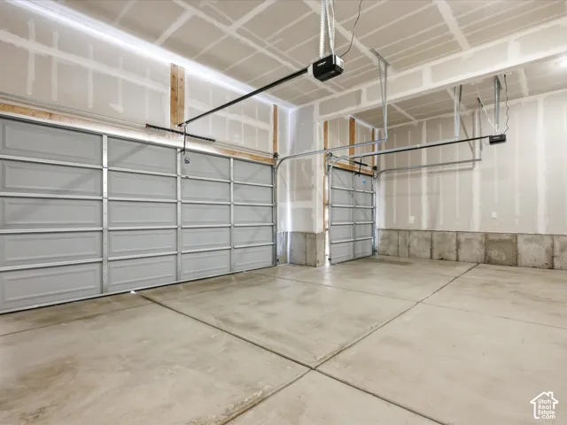 Three-car garage featuring a concrete floor, two automatic garage door openers, and individual metal panel doors