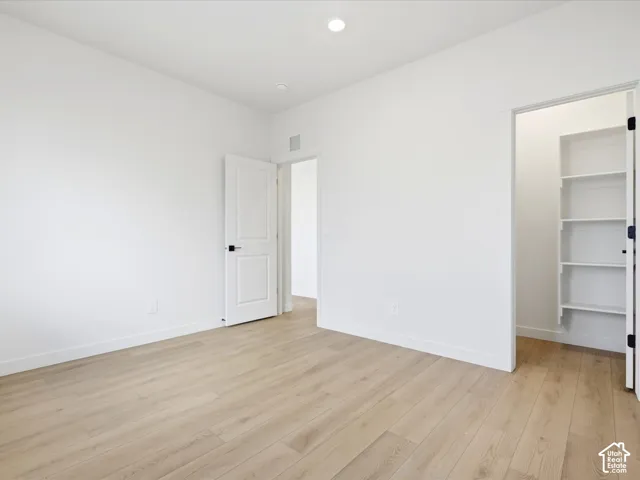 Interior space featuring wood-finish flooring, recessed lighting, multi-panel doors with matte black hardware, and built-in shelving