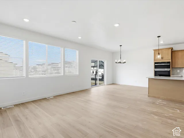 **DISCLAIMER**  Interior package may vary. Open-concept interior featuring wood-finish flooring, recessed lighting, expansive windows, sliding glass door, and cabinetry with integrated double wall ovens
