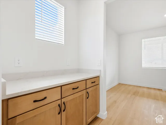 **DISCLAIMER**  Interior package may vary. Light-toned cabinetry featuring matte black hardware, quartz countertops, horizontal blind window treatments, and wood-finish flooring
