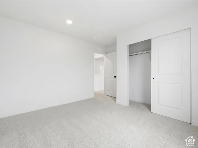 Neutral-toned carpet flooring, recessed lighting, sliding closet door, and interior doors with matte black hardware
