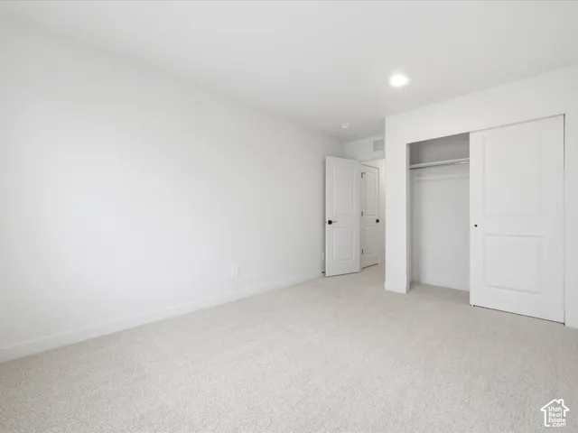 Neutral-toned carpeted flooring, two-panel interior doors, recessed lighting, and a closet with a sliding door