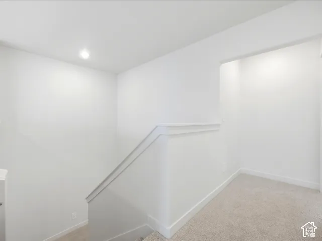 Neutral-toned carpeting, minimalist walls, recessed lighting, and a capped half-wall with trim detail
