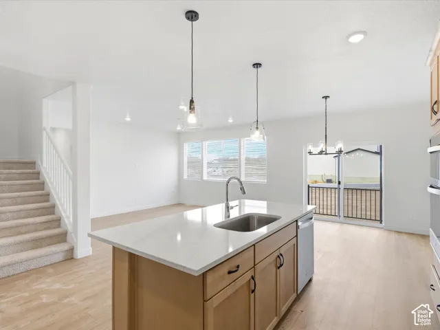 **DISCLAIMER**  Interior package may vary. Kitchen island with stone-finish countertop, undermount stainless steel sink, wood-finish cabinetry, wood-finish flooring, and pendant lighting