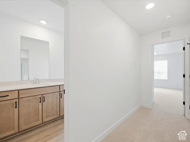 **DISCLAIMER**  Interior package may vary. Vanity featuring wood-finish cabinetry, solid-surface countertop, and integrated sink, complemented by neutral-tone wall-to-wall carpeting and recessed lighting