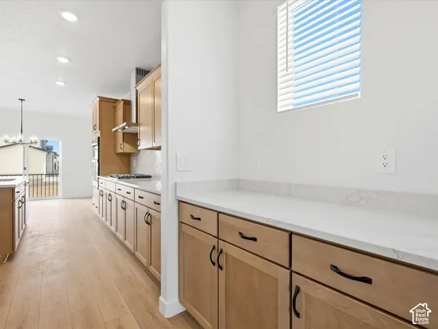 **DISCLAIMER**  Interior package may vary. Kitchen featuring light wood-finish cabinetry, white stone-composite countertops, recessed lighting, and wood-finish flooring
