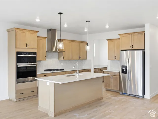 **DISCLAIMER**  Interior package may vary. Kitchen featuring light-finish cabinetry, a central island with a solid-surface countertop, stainless steel appliances, a herringbone tile backsplash, and dual pendant lighting