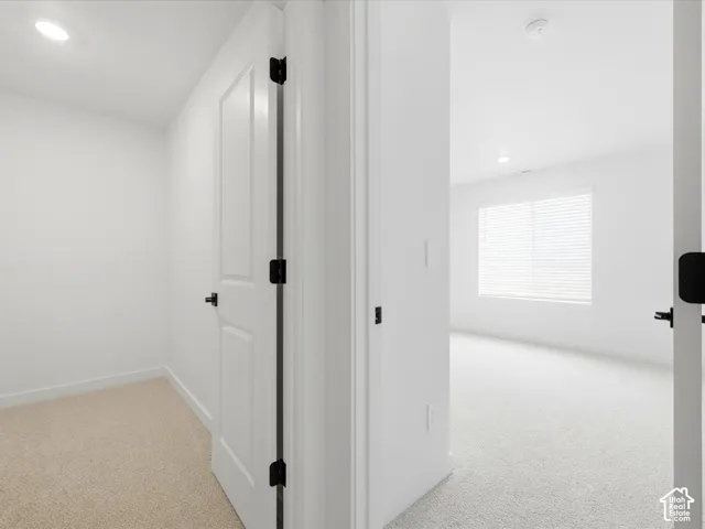 Neutral wall palette featuring paneled interior doors with matte black hardware, carpeted flooring, and recessed ceiling lighting