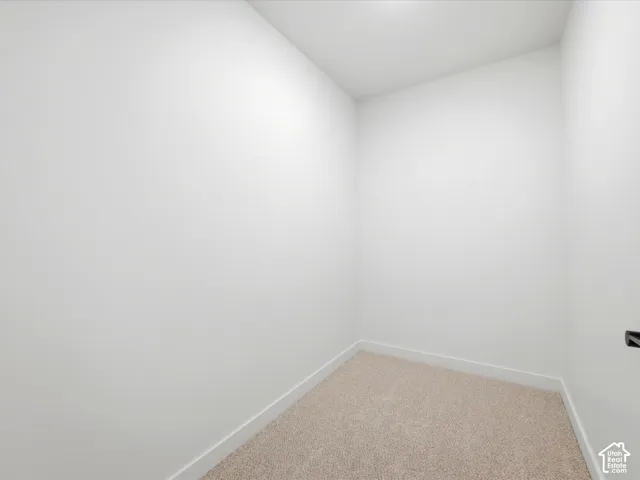 Neutral-toned interior space featuring light-colored wall-to-wall carpeting and crisp white wall finishes