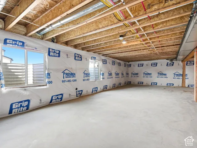 Unfinished basement featuring concrete flooring, exposed wood joist ceiling, and egress windows with exterior window wells