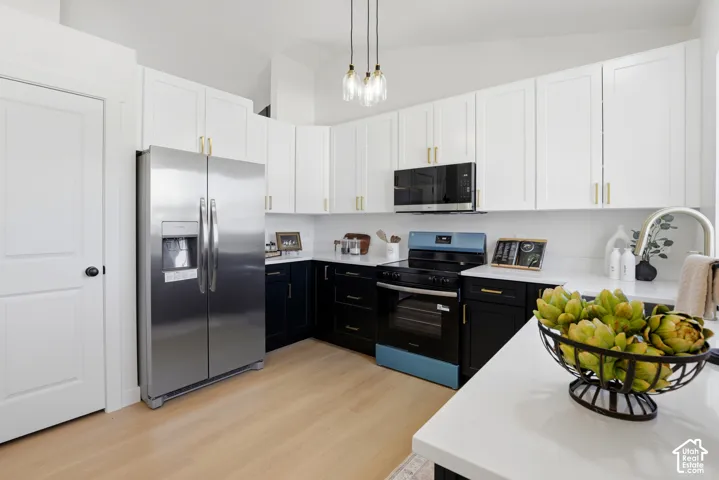 Kitchen featuring white upper and dark lower shaker-style cabinetry, quartz countertops, stainless steel appliances, and wood-finish flooring