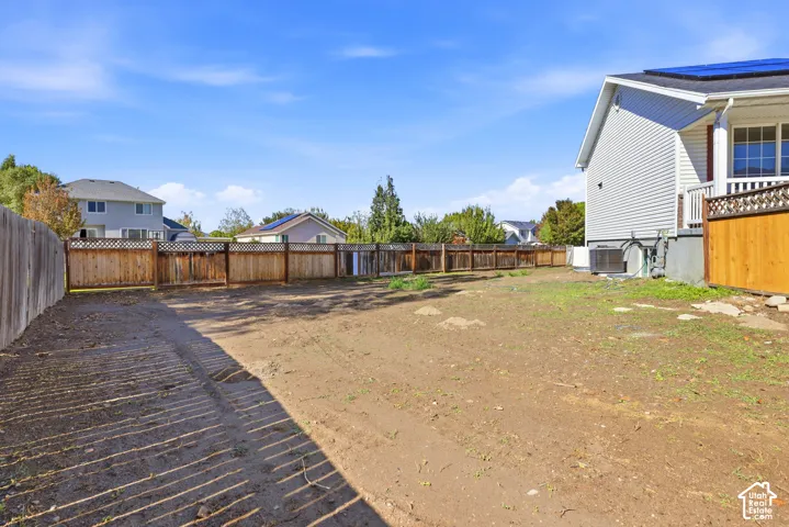 Side yard featuring wood fencing, solar panels on the roofline, and siding exterior