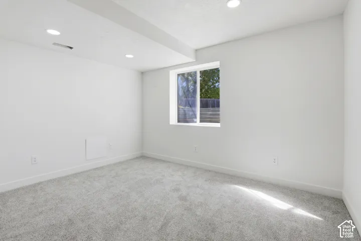 Neutral-toned wall-to-wall carpeting, recessed ceiling lighting, and a single-pane sliding window
