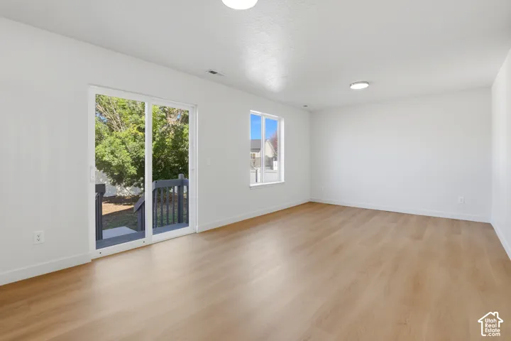 Spacious interior featuring wood-finish flooring, neutral walls, recessed lighting, a large window, and a sliding glass door