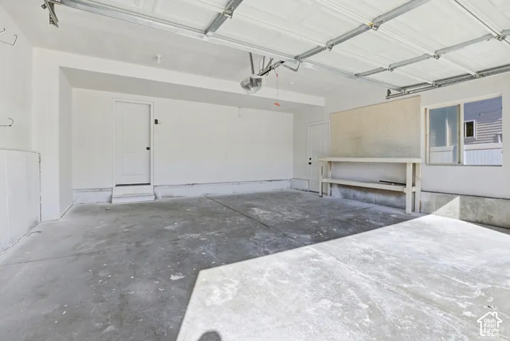 Two-car garage featuring a concrete floor, finished white walls, two entry doors, and a built-in workbench