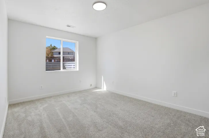 Neutral-toned carpeting, crisp white walls, flush-mount ceiling lighting, and a dual-pane sliding window