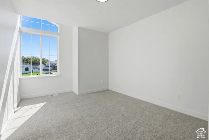 Neutral interior space featuring wall-to-wall carpeting, high ceilings, and a multi-pane arched window