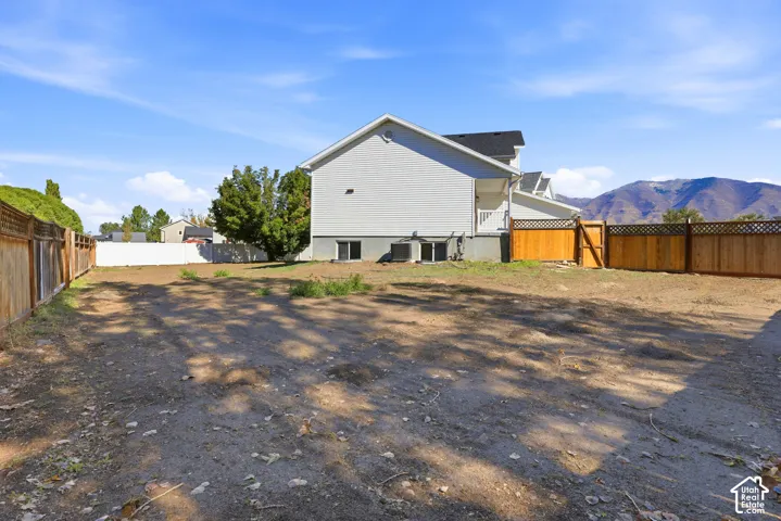 Rear exterior featuring horizontal lap siding, wood-toned lattice-top fencing, and a mountain backdrop