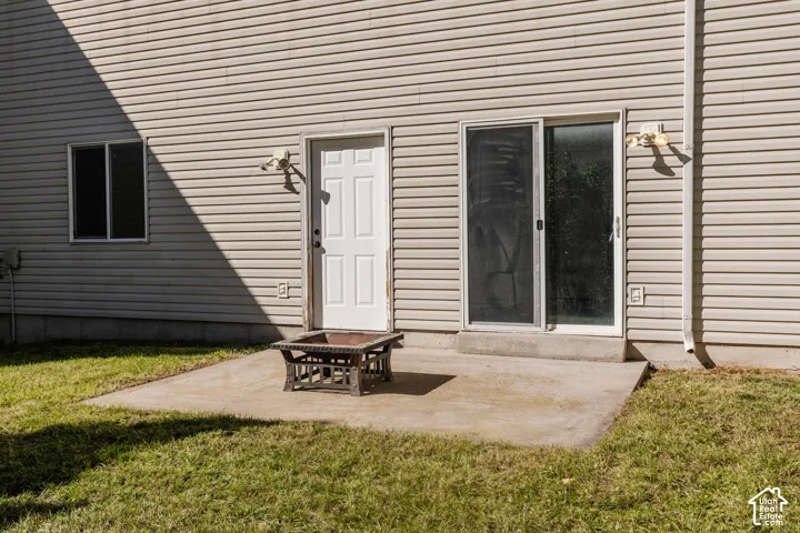 Horizontal vinyl siding exterior featuring a concrete patio, sliding glass door, single-entry door, and wall-mounted exterior lighting