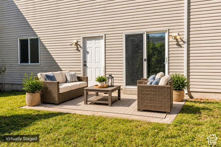 Rear patio featuring concrete hardscaping, horizontal vinyl siding, sliding glass door, and exterior wall-mounted lighting