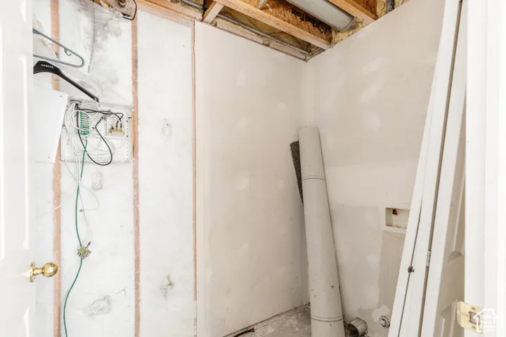 Unfinished interior space featuring exposed insulation, drywall panels, and accessible utility and electrical wiring