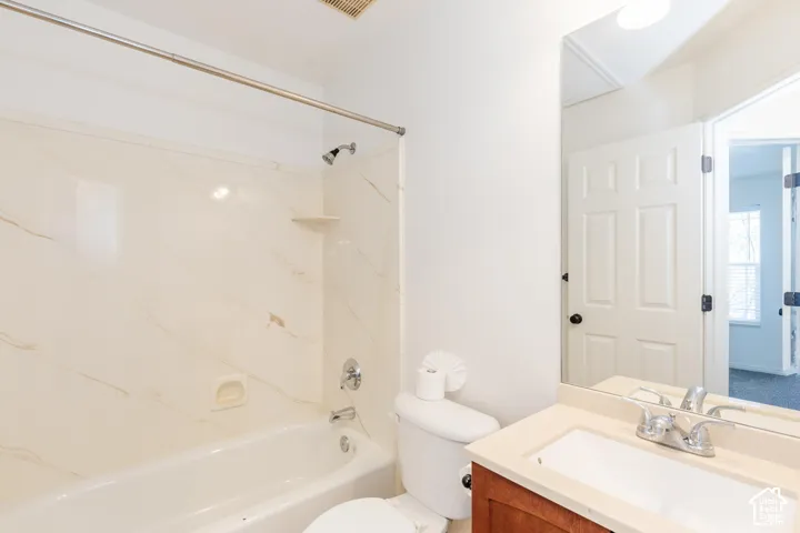Bathroom featuring a tub and shower combination with stone-patterned surround, wood-finish vanity cabinet, solid-surface countertop with integrated basin, and large-format wall-mounted mirror