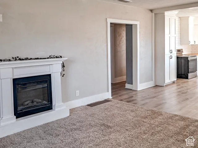Built-in fireplace with white mantel, tall cabinetry, wood-finish flooring, and neutral wall color