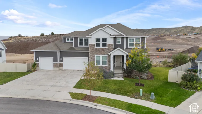 Two-story residential exterior featuring dark siding, stone veneer accents, multi-gabled roofline, three-car garage, and concrete driveway