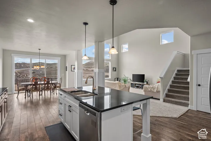 Kitchen island with a solid surface countertop, stainless steel dual-basin sink, and pendant lighting