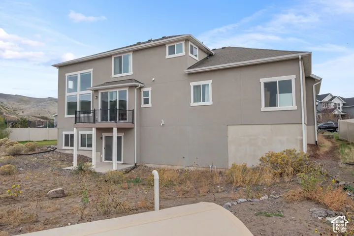 Multi-level exterior featuring stucco siding, a rear elevated deck with metal railing, floor-to-ceiling windows, and mountain scenery