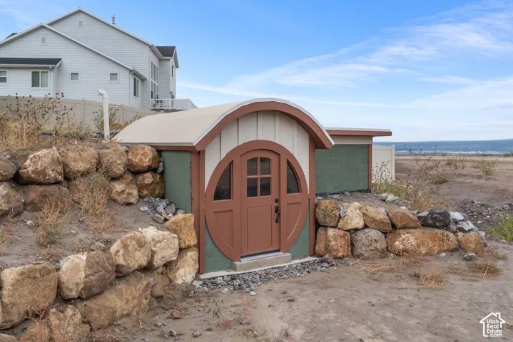 Earth-sheltered structure featuring a reinforced stone retaining wall, arched doorway, and vertical panel siding