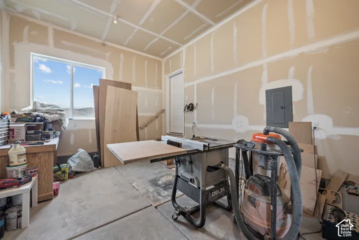 Finished space with drywall and taping, single-pane window, concrete flooring, exterior-style door, and integrated electrical panel