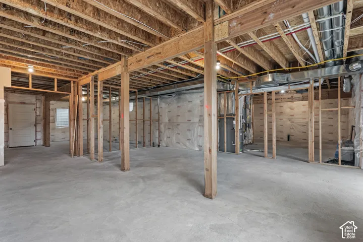 Unfinished lower level featuring exposed wood joists, concrete flooring, structural support columns, metal ductwork, and vapor barrier wall sheeting
