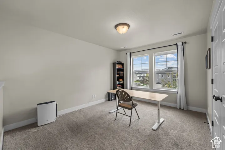 Neutral-toned interior space featuring carpeting, dual-pane windows, and white paneled doors